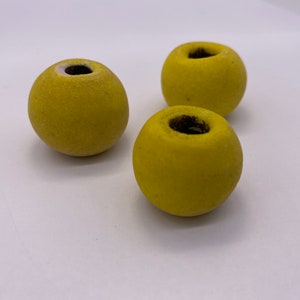 May include: Three yellow ceramic spheres with a small hole in the top. The spheres are smooth and have a matte finish.