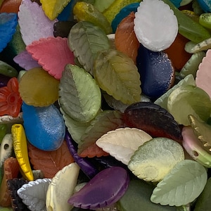 May include: Assortment of colourful glass leaf-shaped beads. The beads are in various shades of green, blue, pink, purple, brown, and white.