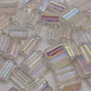 May include: A collection of iridescent glass beads with a ribbed texture. The beads are clear with a rainbow sheen.
