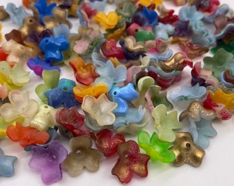 Może przedstawiać: Zestaw kolorowych plastikowych koralików w kształcie kwiatów. Korale są przezroczyste i mają różne kolory, w tym niebieski, zielony, czerwony, żółty i fioletowy.