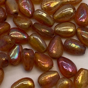 Honey colored glass teardrops with a warm pink and gold iridescent finish. German. (20 pieces per price)