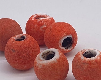 Peut inclure: Six perles en céramique orange avec des centres blancs et un trou au milieu. Les perles sont texturées et ont une surface rugueuse.