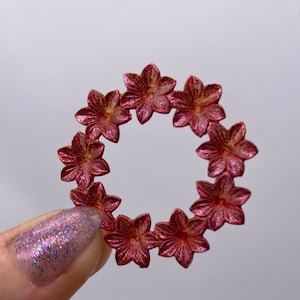 May include: A red metal wreath with a floral design. The wreath is made of individual flowers that are connected together to form a circle.