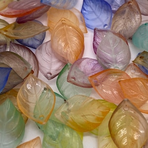 May include: Assortment of translucent leaf-shaped beads in various pastel colors, including pink, blue, green, and yellow. The beads have a hole at the top for stringing.