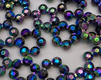 May include: A group of iridescent black and blue round rhinestones with a faceted design. Each rhinestone has a hole in the center, suggesting they are meant to be strung together.
