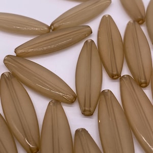 May include: A group of translucent brown oval-shaped beads. The beads have a smooth, glossy finish and are arranged in a random pattern.