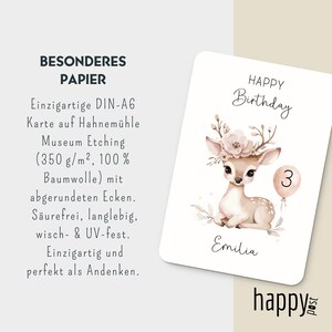 May include: A birthday card with a watercolor illustration of a fawn wearing a floral crown and holding a balloon with the number 3. The card has the text "Happy Birthday" and the name "Emilia". The card is white with rounded corners.