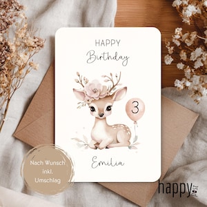 May include: A birthday card with a watercolor illustration of a fawn wearing a floral crown and holding a balloon with the number 3. The card reads "Happy Birthday" and "Emilia". Includes a brown envelope.