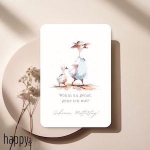May include: A watercolor-style greeting card featuring a mother goose and gosling walking together. The card has the text "Wohin du gehst, gehe ich mit!" and "Schönen Muttertag!" in black script. The card is on a beige background.