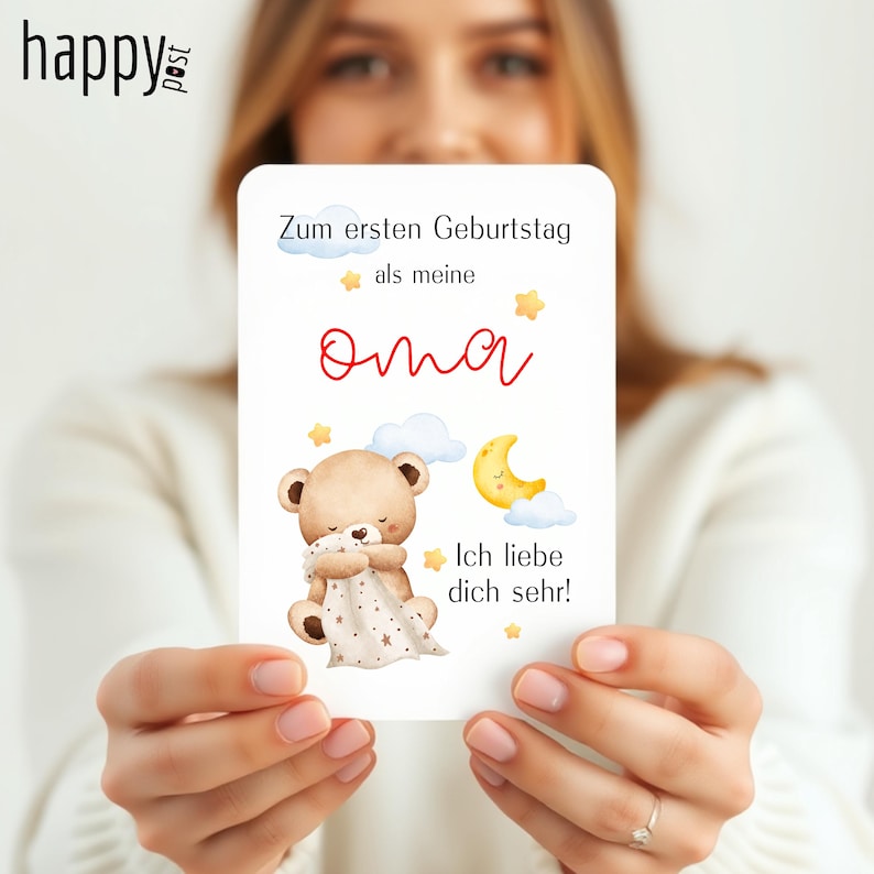 May include: A white card with German text and a teddy bear illustration. The card reads "Zum ersten Geburtstag als meine Oma" and "Ich liebe dich sehr!" A teddy bear is hugging a blanket with stars, and a yellow moon is also shown.