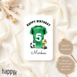 May include: A birthday card featuring a green soccer jersey with the number 5, a soccer ball, and a trophy. The words "HAPPY BIRTHDAY" are at the top, and the name "Markus" is written below the jersey. The card is on a white background.