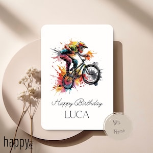 May include: A white birthday card with a colorful illustration of a BMX rider in action. The card features the text "Happy Birthday LUCA" in elegant script. A splash of vibrant colors surrounds the rider, adding a dynamic touch to the design.