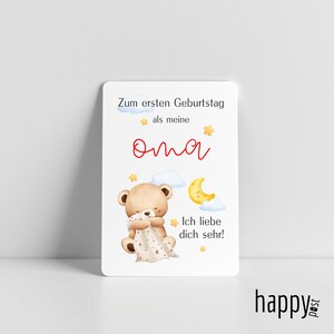 May include: A white card with a teddy bear illustration, a crescent moon, and text in German. The card reads "Zum ersten Geburtstag als meine Oma. Ich liebe dich sehr!" in red and black. The card has a "happy post" logo.