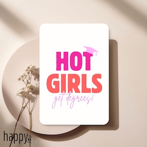 Może przedstawiać: Biała prostokątna karta z napisem "HOT GIRLS get degrees!" w kolorze różowym i pomarańczowym, z ikoną czapki absolwenta. Karta leży na beżowym talerzu z suszonymi kwiatami.