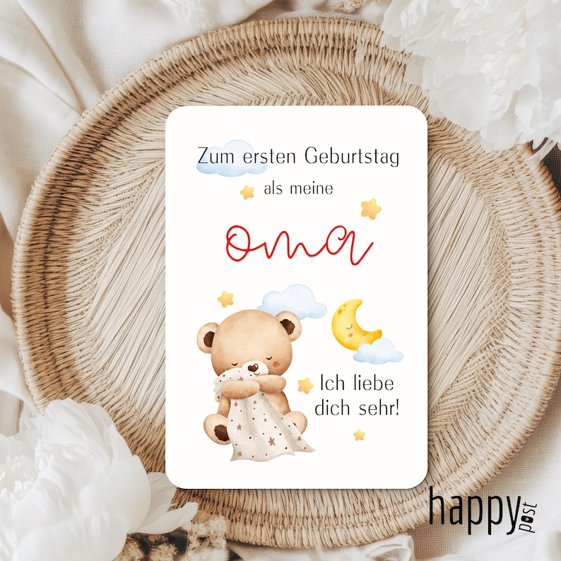 May include: A rectangular card with text and illustrations. The text reads "Zum ersten Geburtstag als meine Oma" and "Ich liebe dich sehr!". The illustrations include a teddy bear, clouds, a crescent moon, and stars. The card has a light background.