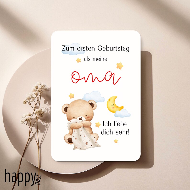 May include: A white card with German text and a watercolor illustration of a teddy bear, moon, and stars. The text reads "Zum ersten Geburtstag als meine Oma. Ich liebe dich sehr!" in red and black.