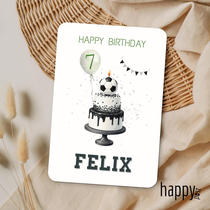 May include: A birthday card with a soccer theme. The card features a two-tiered cake with a soccer ball on top, a balloon with the number 7, and the name FELIX. The words "HAPPY BIRTHDAY" are at the top.