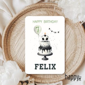 May include: A birthday card with a soccer theme. The card features a two-tiered cake topped with a soccer ball, a balloon with the number 7, and the name "FELIX". The words "HAPPY BIRTHDAY" are at the top.