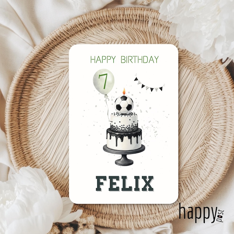 May include: A birthday card with a soccer theme. The card features a two-tiered cake topped with a soccer ball, a balloon with the number 7, and the name "FELIX". The words "HAPPY BIRTHDAY" are at the top.