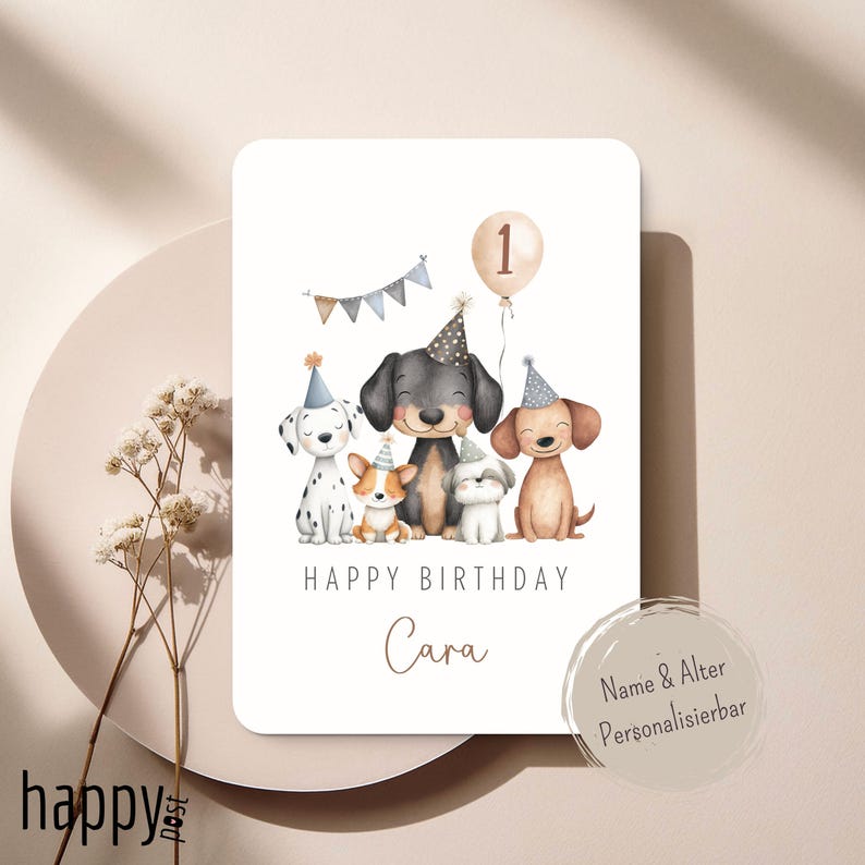 May include: A birthday card featuring five cartoon dogs wearing party hats. A balloon with the number 1 floats above them. The words "Happy Birthday" and the name "Cara" are written on the card. A banner with small flags is also present.