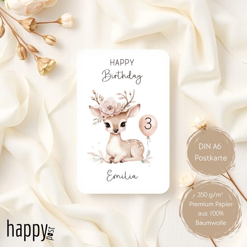 May include: A birthday card featuring a watercolor illustration of a fawn with floral accents and a balloon with the number 3. The card reads "Happy Birthday" and "Emilia". The card is a DIN A6 postcard made of premium cotton paper.