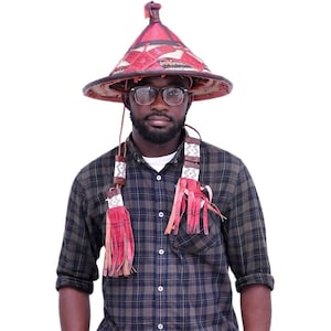 以下が含まれることがあります： 赤い茶色の房飾りの付いた円錐形の帽子、格子縞のシャツ、青いジーンズ、眼鏡をかけた男性