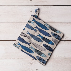 Può includere: Un guanto da forno beige con un motivo a pesce blu e bianco. Il guanto da forno ha un anello per appenderlo.