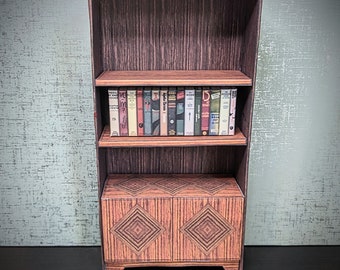 May include: A miniature wooden bookshelf with two shelves and a cabinet with two doors. The shelves are filled with miniature books. The cabinet doors have a diamond pattern.