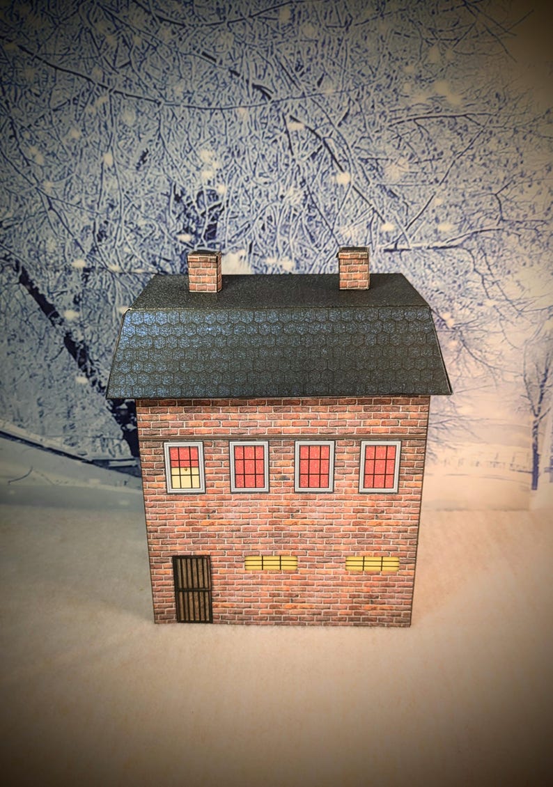 May include: A small, brick building with a gray roof and two chimneys. The building has four windows with red frames and two windows with yellow frames. The building has a black door with a metal grate.