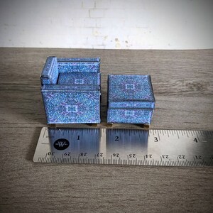 May include: A miniature blue and purple patterned armchair and matching side table. The furniture is made of paper and is approximately 2 inches tall.