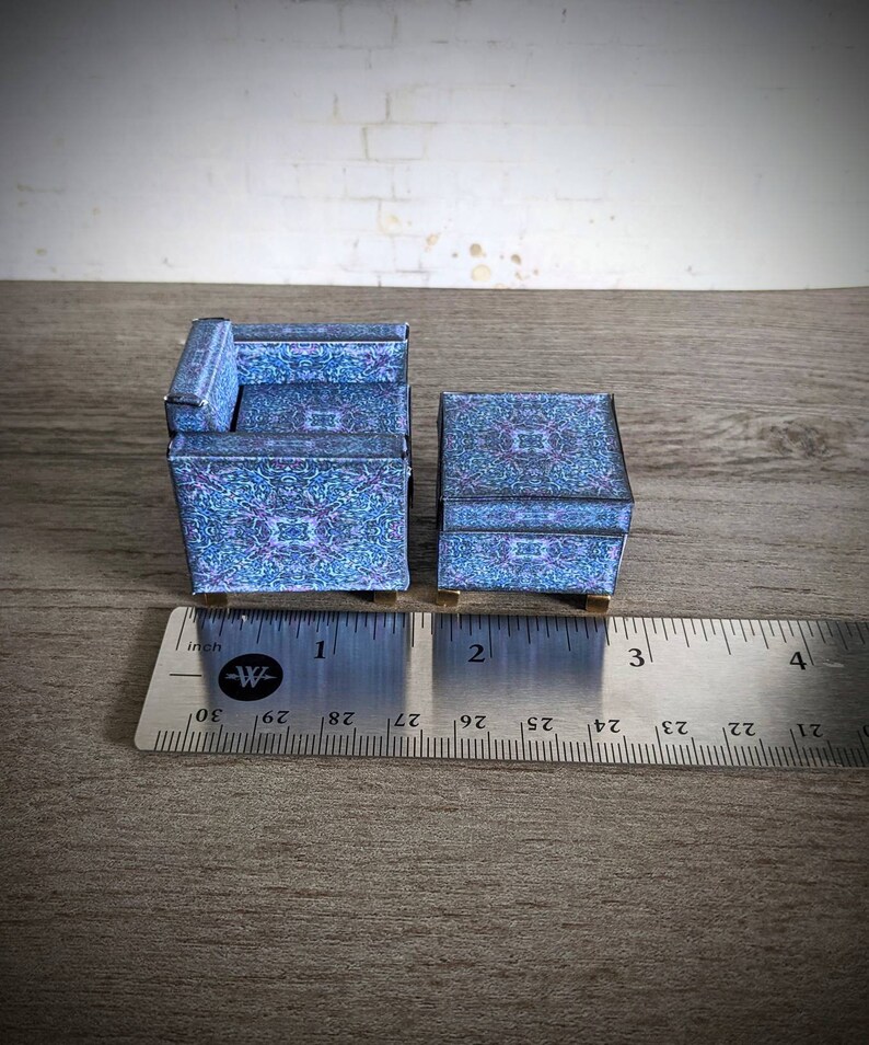 May include: A miniature blue and purple patterned armchair and matching side table. The furniture is made of paper and is approximately 2 inches tall.