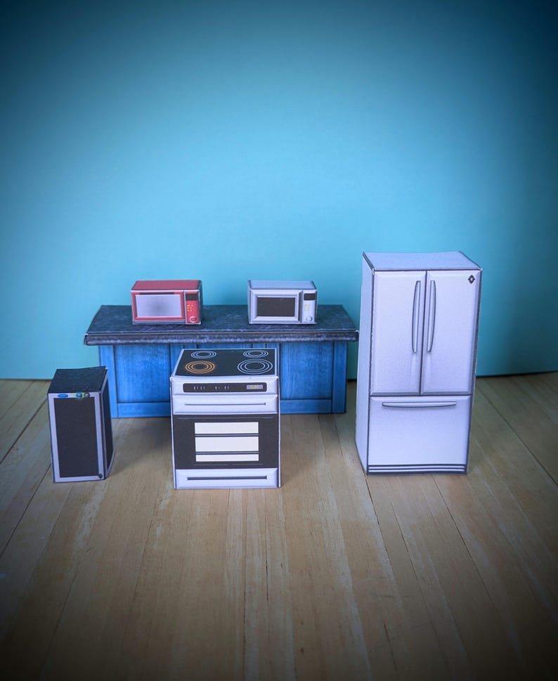 Pode incluir: Um conjunto de eletrodom&eacute;sticos de cozinha em miniatura, incluindo um forno de micro-ondas vermelho, um forno de micro-ondas branco, um forno branco com um fog&atilde;o preto, uma geladeira branca e um alto-falante preto. Os eletrodom&eacute;sticos est&atilde;o dispostos em uma bancada azul com um piso de madeira.