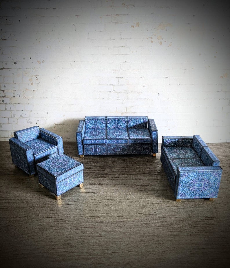 May include: A blue patterned living room set with a sofa, two armchairs, and a matching ottoman. The furniture is arranged on a wood floor in front of a white brick wall.