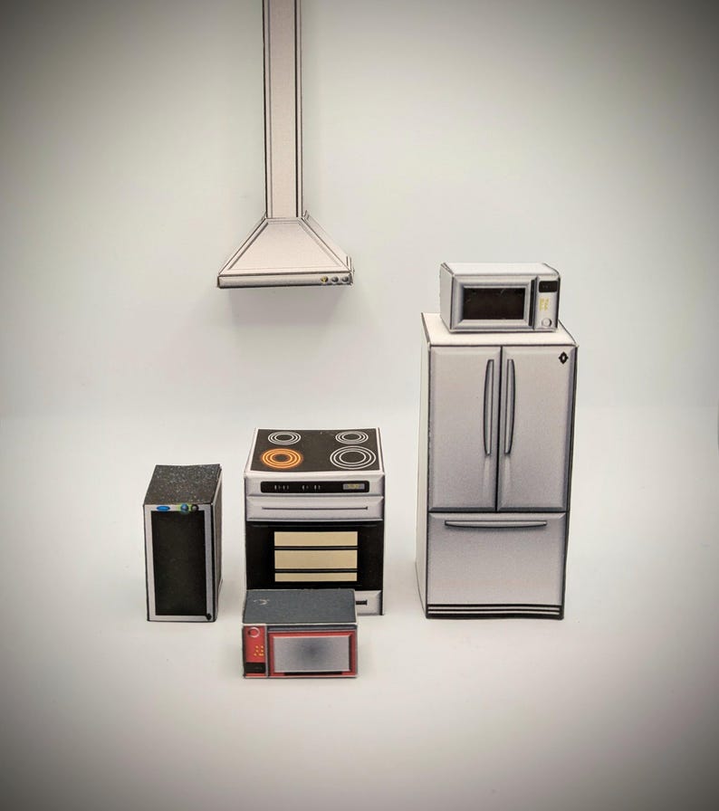 Pode incluir: Um conjunto de cinco eletrodom&eacute;sticos de cozinha em miniatura, incluindo um refrigerador, um forno, um fog&atilde;o, um forno de microondas e um forno de microondas menor. Os eletrodom&eacute;sticos s&atilde;o todos brancos com detalhes pretos e s&atilde;o feitos de papel.