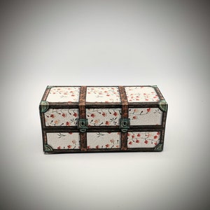 May include: A small, rectangular wooden chest with a floral pattern and metal clasps. The chest is closed and has a vintage look.