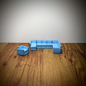May include: A blue sectional sofa with a matching blue armchair. The sofa is made up of multiple individual pieces that can be arranged in different configurations. The furniture is on a wooden floor.