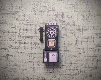 May include: A black vintage-style rotary phone with a white dial and a black receiver. The phone has a sign that reads "Local Call 10c Long Distance".