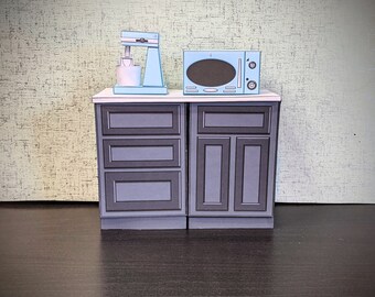 May include: A set of two kitchen cabinets with a light blue microwave and a light blue stand mixer on top. The cabinets are dark gray with black trim.