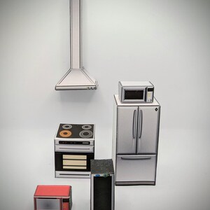 Pode incluir: Um conjunto de cinco eletrodom&eacute;sticos de cozinha em miniatura, incluindo um fog&atilde;o, um forno, um refrigerador, um forno de microondas e uma adega de vinhos. Os eletrodom&eacute;sticos s&atilde;o feitos de papel e s&atilde;o pintados em um estilo realista. Os eletrodom&eacute;sticos s&atilde;o todos brancos e prateados, exceto o forno de microondas, que &eacute; vermelho.