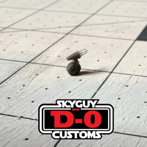 May include: A small, dark gray, spherical miniature figure with a protruding antenna-like attachment on top. The image includes a logo at the bottom with the text SKYGUY MINI D-O CUSTOMS in white and red lettering on a black background.