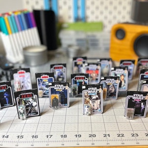 May include: A collection of Star Wars action figure cards featuring various characters, including Darth Vader, R2-D2, and a Stormtrooper. The cards are displayed on a grid with numbers 13 through 25.