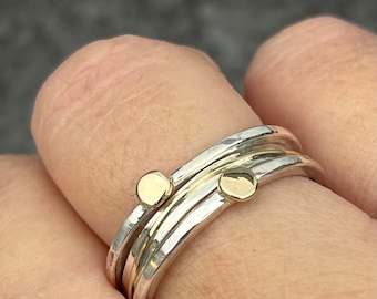 May include: A silver and gold ring with two gold accents. The ring is made of multiple bands that are twisted together.