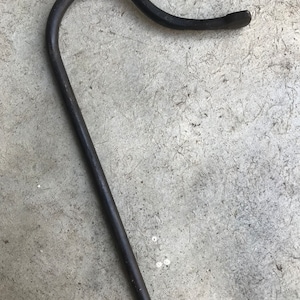 May include: A black metal hook with a curved handle. The hook is made from a single piece of metal and has a smooth finish.