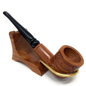 Puede incluir: Una pipa de fumar de madera con una boquilla negra y un soporte de madera marrón. La pipa tiene un diseño tallado y una cazoleta para tabaco.