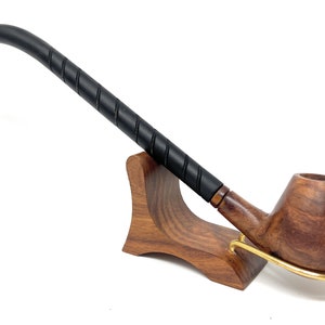 May include: A wooden pipe with a black, twisted stem and a brown bowl. The pipe is resting on a wooden stand.