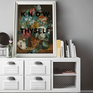 May include: A framed wall art print featuring a classical floral still life painting in an orange vase, with the black text KNOW THYSELF overlaid on the image. The artwork is displayed in a silver frame with a white border.