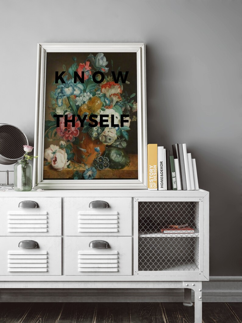 May include: A framed wall art print featuring a classical floral still life painting in an orange vase, with the black text KNOW THYSELF overlaid on the image. The artwork is displayed in a silver frame with a white border.