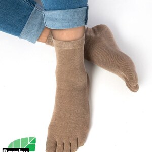 May include: A pair of brown toe socks made from bamboo. The socks are shown on a person's feet with the toes separated. The socks are ankle-high and have a ribbed texture.