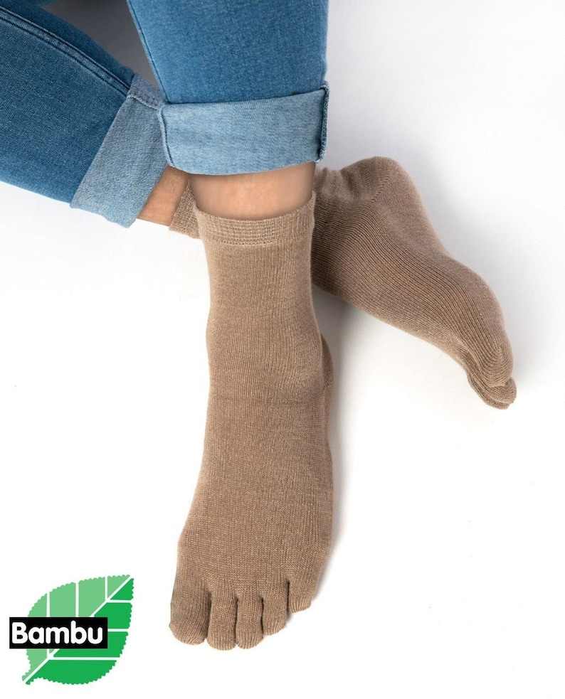 May include: A pair of brown toe socks made from bamboo. The socks are shown on a person's feet with the toes separated. The socks are ankle-high and have a ribbed texture.