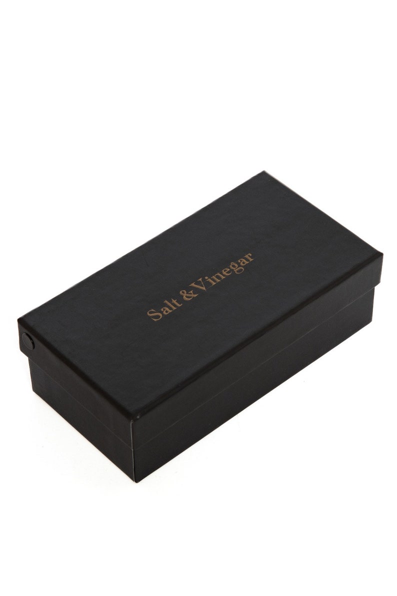 Puede incluir: Una caja rectangular negra con las palabras "Salt & Vinegar" impresas en dorado. La caja tiene una superficie texturizada y una tapa que encaja perfectamente. La caja est&aacute; sobre un fondo blanco.